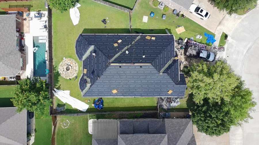 Aerial drone view of a Frame Restoration roof replacement in progress in McKinney, Texas, with fresh synthetic underlayment installed over the bare wood decking