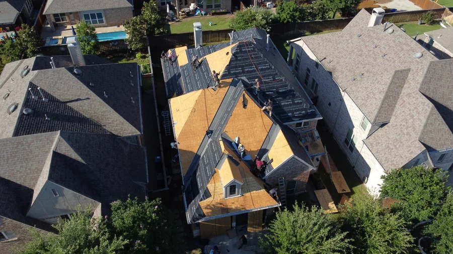 Aerial view of a Frame Restoration roof replacement in progress in The Colony, Texas, showing exposed decking and underlayment work